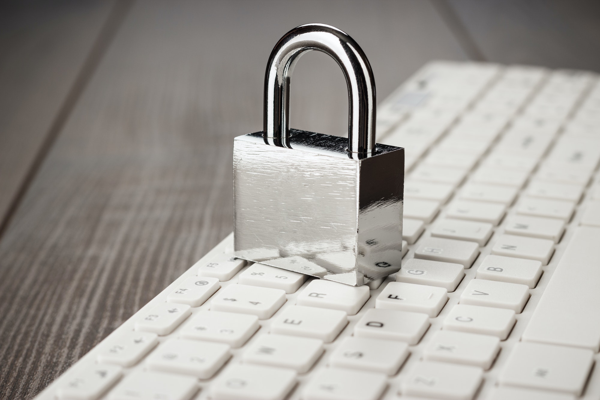 Padlock And White Computer Keyboard On The Wooden Office Table